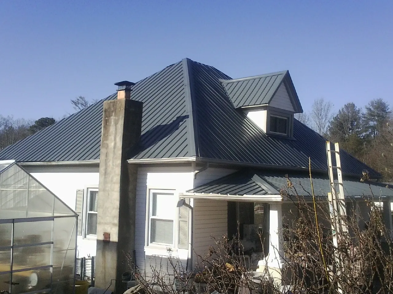 Dark blue standing seam metal roof on a white farmhouse with dormer — Slate & Tile Roof Repair by Roofing Brothers in Annandale On Hudson
