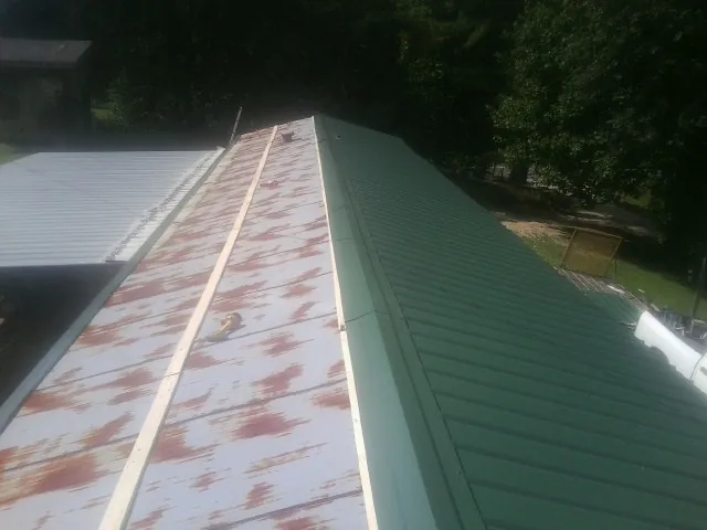 Old rusted panels beside newly installed green metal roofing — Wind Damage Roof Repair by Roofing Brothers in Annandale On Hudson