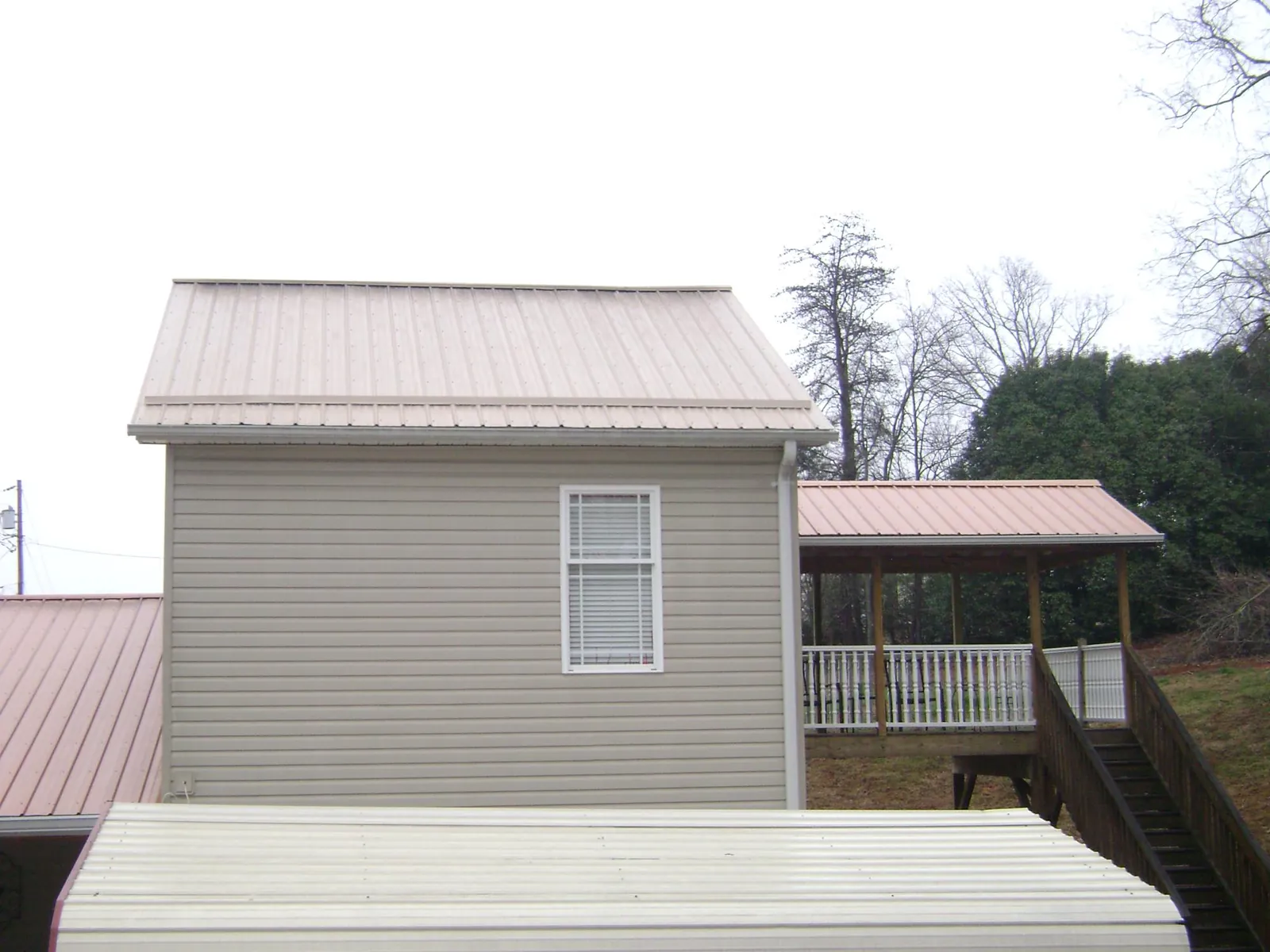 Tan metal roofs on a two story addition and attached porch, from a Roof Replacement job in Annandale On Hudson