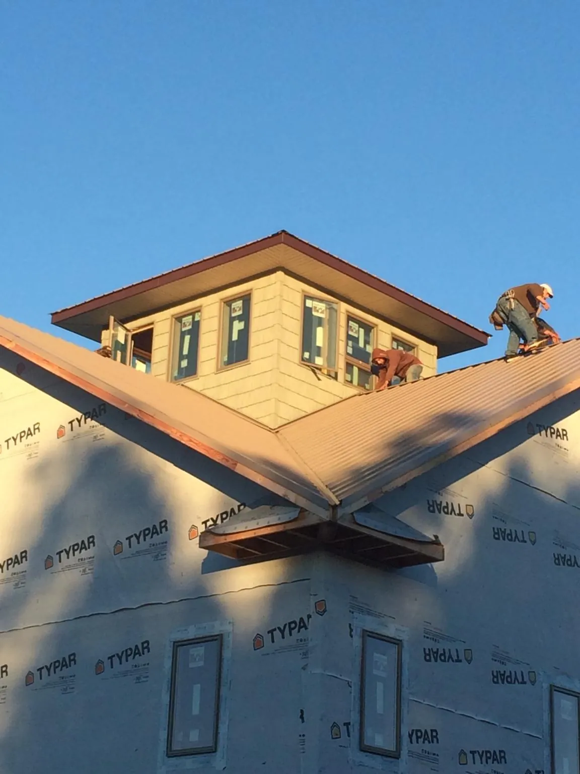 Roofers working around a rooftop cupola on a new metal roof at sunset — Roof Waterproofing in Annandale On Hudson by Roofing Brothers